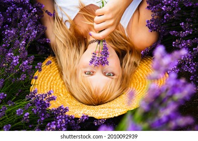 Beautiful woman with blond hair is lying down in lavender flowers field 
