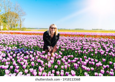 Beautiful Woman with blond hair standing in colorful tulip flower fields in Amsterdam region, Holland, Netherlands. Magical Netherlands landscape with tulip field in Holland Trevel and spring concept