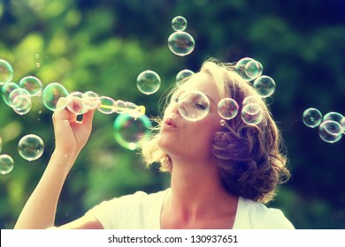 a beautiful woman blowing bubbles - Powered by Shutterstock