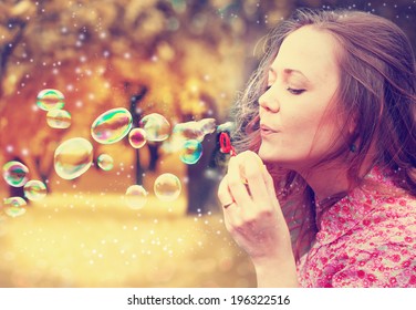 Beautiful woman blowing bubbles in park - Powered by Shutterstock