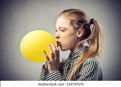 beautiful woman is blowing up a yellow balloon