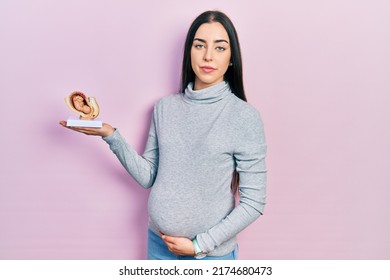 Beautiful Woman With Blue Eyes Expecting A Baby, Holding Anatomic Fetus Thinking Attitude And Sober Expression Looking Self Confident 