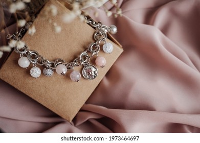 Beautiful woman bracelet with white and pink beads on the craft box. Image with selective focus and toning.