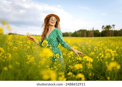 Beautiful woman in bright dress walking through flowering field, touching yellow flowers. Fashion, beauty concept. Summer landscape. - Powered by Shutterstock