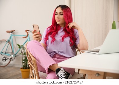 Beautiful Woman With Bright Pink Hair Using Mobile Phone At Home