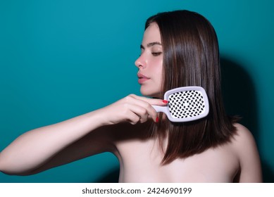 Beautiful woman with brush combing hair. Beauty girl with straight hair isolated on studio background. Woman hold hairbrush near face. Healthy hair. Hairstyle and hair care concept. Shiny hairs.