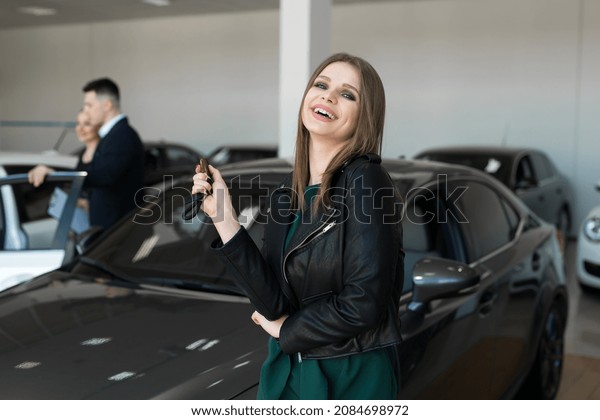 Beautiful woman or car salesman stand holding a\
new car remote key in a car\
showroom