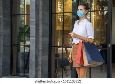 beautiful woman carries a shopping bag and wears a mask to prevent Covit 19. Walking out of the shopping mall