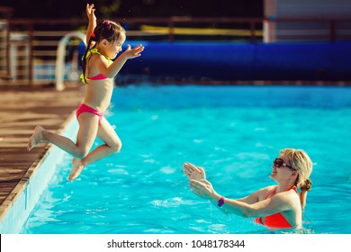 Beautiful Woman Catches Little Girl Jumping In Pool Against Sea