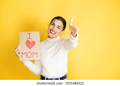 Beautiful Woman Celebrating Mothers Day Holding Poster Love Mom Message Looking At The Camera Smiling With Open Arms For Hug