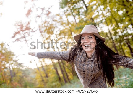 Beautiful woman in checked coat and hat, autumn forest