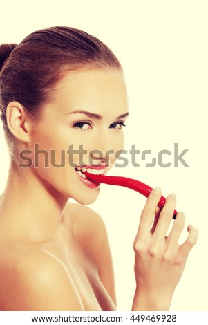 Beautiful woman with chili pepper in mouth.