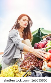 Beautiful Woman Choosing A Fruit Outdoors In The Bio Market