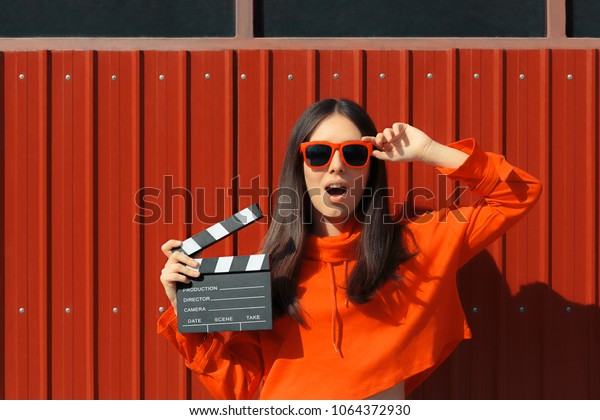 Beautiful Woman with\
Cinema Clapper on Red Background. Cool model girl with film slate\
at casting audition\
