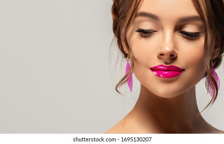 Beautiful woman with clean skin on her face. Beauty, cosmetics and cosmetology. Fashion earrings as accessories. Cosmetics and makeup, fuchsia lips.
