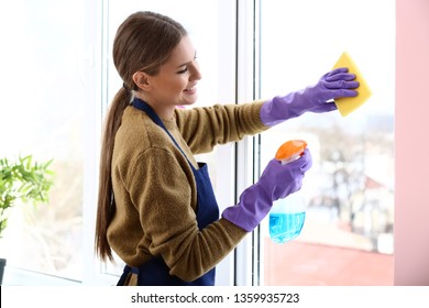 Beautiful woman cleaning window at home