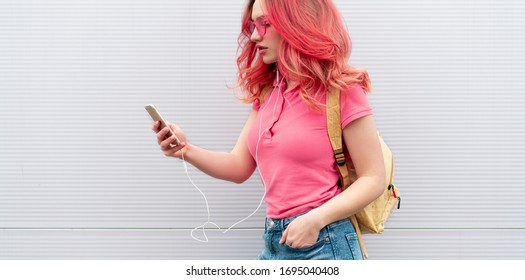 Beautiful woman with colored pink hairs, wireless headphones and smartphone over grey background - Powered by Shutterstock