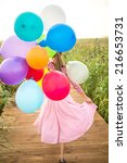  Beautiful woman with colorful balloons walking on wooden bridge. focus on balloons