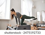 Beautiful woman in comfy sportswear practising during pilates lesson.