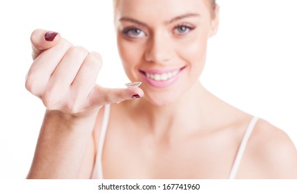 Schöne Frau mit einer Kontaktlinse, die auf ihrem Finger ausbalanciert ist, die Kamera anzulächeln, bevor sie sie in ihr Auge einstecken
