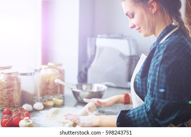 Beautiful woman cooking cake in kitchen standing near desk