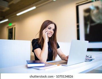 Schöne Frau Kopienschreiber spricht auf Handy während der Arbeit auf Laptop-Computer, sitzend in Kaffeehaus. Manager von weiblichen Inhalten, der über Mobiltelefon bei der Suche nach Netbook-Informationen für das Projekt anruft