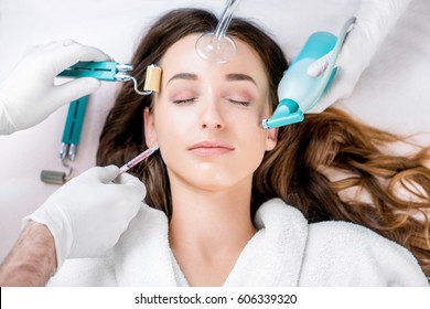 Beautiful Woman With Cosmetology Tools Lying On The Medical Couch. Facial Treatment Concept