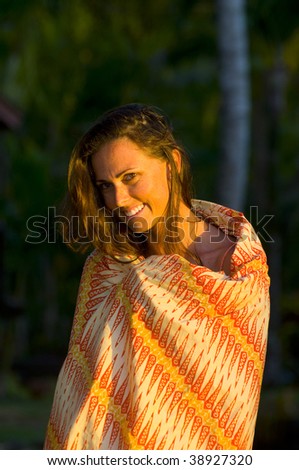beautiful woman covered up with a sarong on the beach at sunset