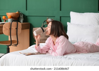Beautiful woman with cup of coffee and magazine in bedroom