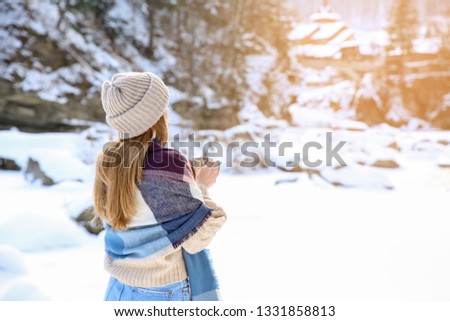 Beautiful woman with cup of hot mulled wine at snowy resort