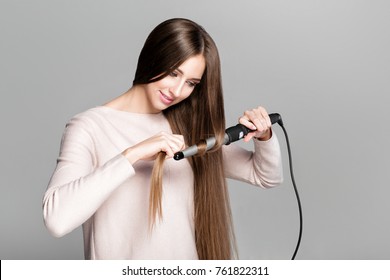 Beautiful Woman Curling Long Hair Using Curling Iron. 