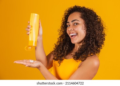 Beautiful Woman With Curly Hair Applying Cream To Her Hair. Afro Woman With Hair Product In Hand