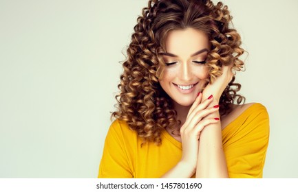 Beautiful Woman With Curly Hair And Red Nails Manicure . Girl Laughs Shyly Closes Her Face With A Hand .