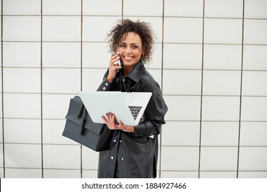 Beautiful Woman With Curly Hair Talking On The Phone And Carrying An Open Laptop