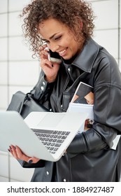 Beautiful Woman With Curly Hair Talking On The Phone And Carrying An Open Laptop