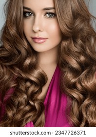 Beautiful woman with curly volume hairstyle, long luxurious hair and beauty make-up, glamorous look face portrait for luxury fashion and natural cosmetics idea