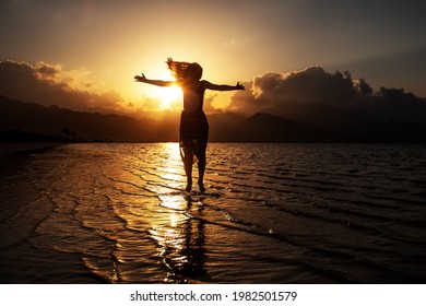 Schöne Frau, die bei Sonnenuntergang am Meer tanzt
