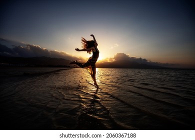 Beautiful woman dancing by the sea at sunset - Powered by Shutterstock