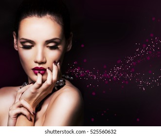 beautiful woman with dark makeup and purple lipstick posing on black background
