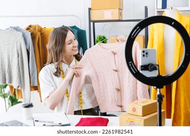 Beautiful woman describe selling clothes on camera live broadcast on social network at home, Online selling clothes on social media. Vlogger woman influencer, SME retail store owner. - Shutterstock ID 2261982541