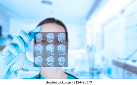 Beautiful Woman Doctor Radiologist, Oncologist Looks At MRI Images Of A Child. Soft Blurred Clinic Background. High Quality Photo