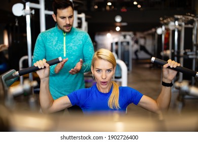 Beautiful woman doing exercises in gym with personal trainer