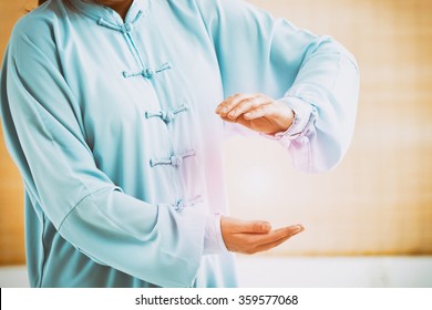 Beautiful woman doing qi gong tai chi exercise or reiki wearing professional, original Chinese clothes at gym