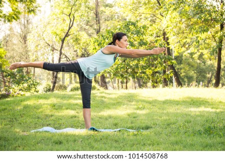 Beautiful woman doing yoga exercises in the park. Concept of healthy lifestyle.