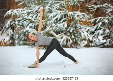 Beautiful Woman Doing Yoga Outdoors In The Snow