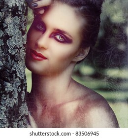 Beautiful Woman With Dramatic Eye Make-up, Gray Manicure & Beehive Hairstyle Outdoors Next To The Tree With Natural Bokeh Effect, Split Tone Colour For Fashion Look