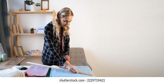 Beautiful woman drawing pattern on fabric with ruler, hand making clothes in home interior. Creative skills design. hobbies and lifestyle concept - Shutterstock ID 2229719421