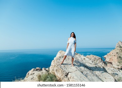 Beautiful woman in a dress with long hair travels a beautiful sea landscape