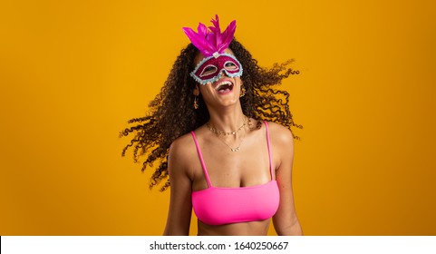 Beautiful woman dressed for carnival night. Smiling woman ready to enjoy the carnival with a colorful mask. Pointing up.