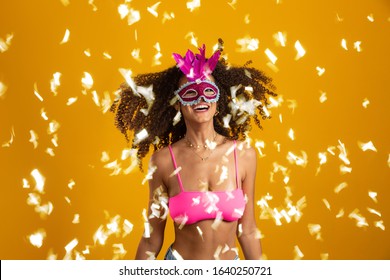 Beautiful woman dressed for carnival night. Smiling woman ready to enjoy the carnival with a colorful mask and confetti.